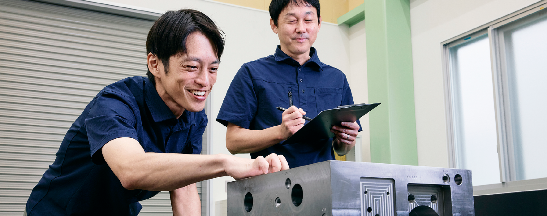 二人の男性が機械を触りながら作業してる写真